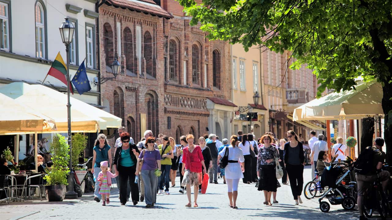 A street in Lithuania with pedestrians and old buildings in the background.