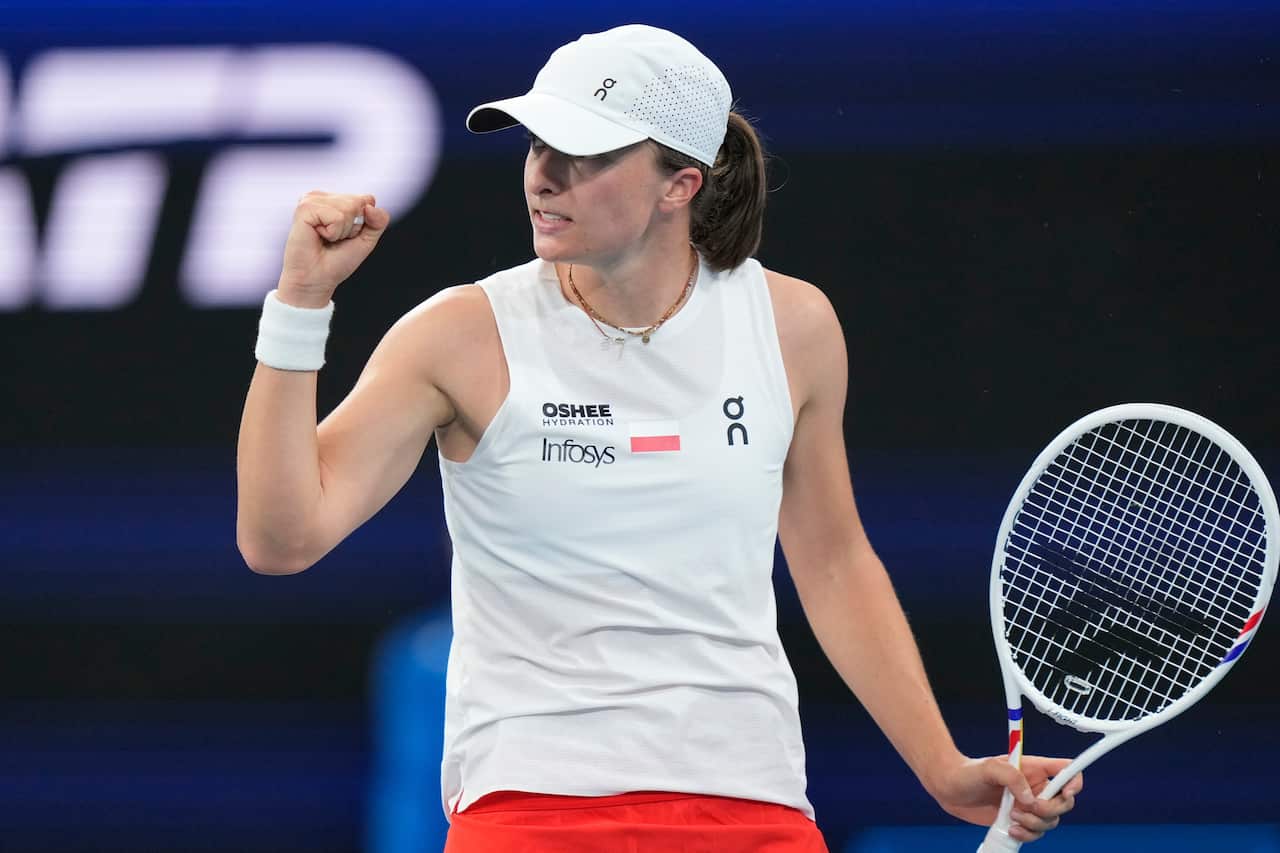A woman holding a tennis racquet and raising a fist in the air.