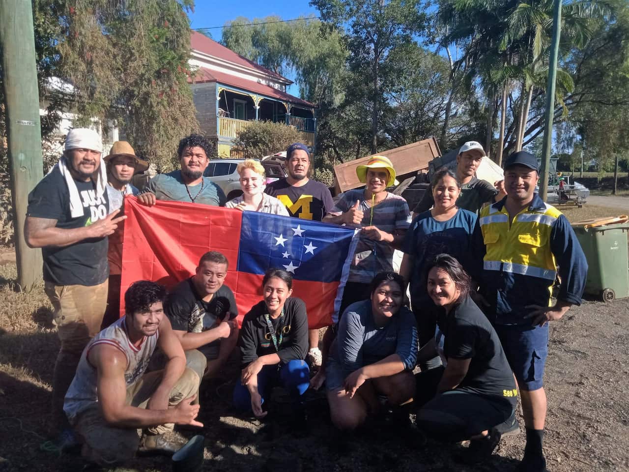 Van Tamoto Leaula (top right) and Keyson Niupulusu (bottom left) stand with their community members during the clean-up efforts in Lismore.