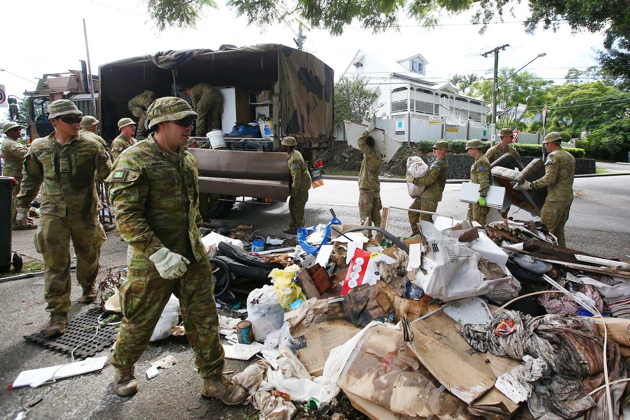 ADF personnel are seen helping clean up a street affected by floodwater.