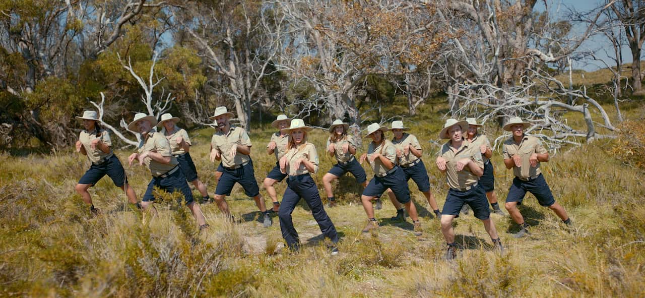 Kylie Minogue leading a group of dancers, imitating quokkas, dancing in scrub.