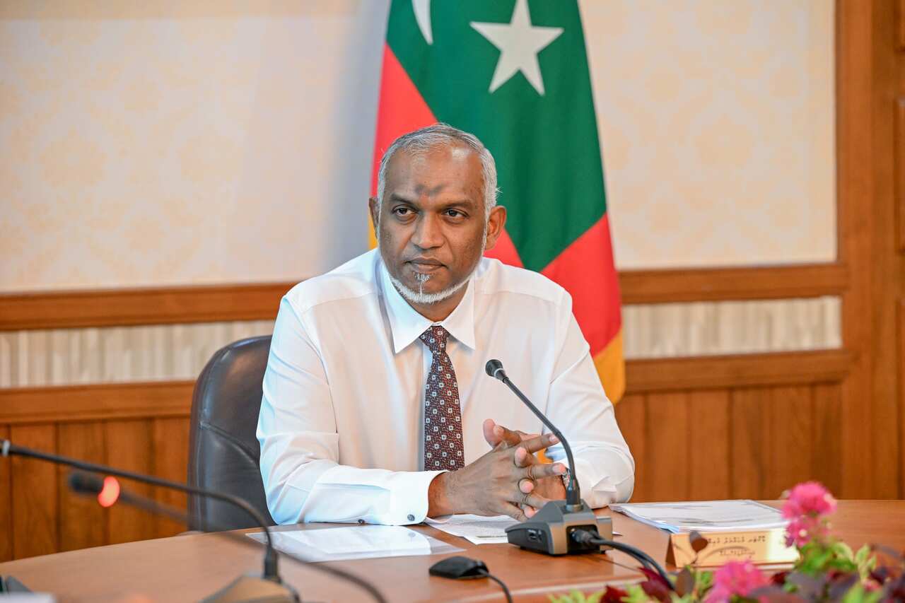 A man in a white shirt sits at a desk