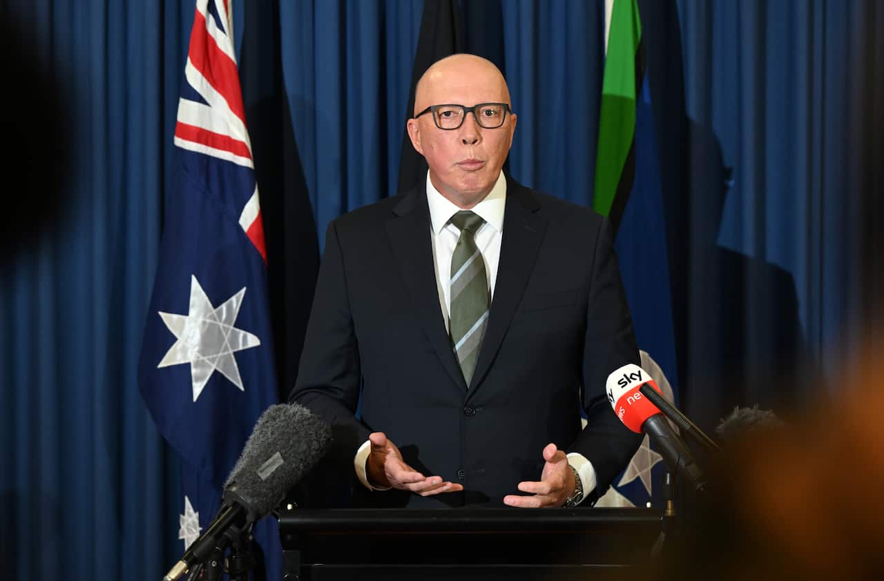 Peter Dutton wearing a suit and tie and talking inside from behind a lectern. There are microphones in front of him.