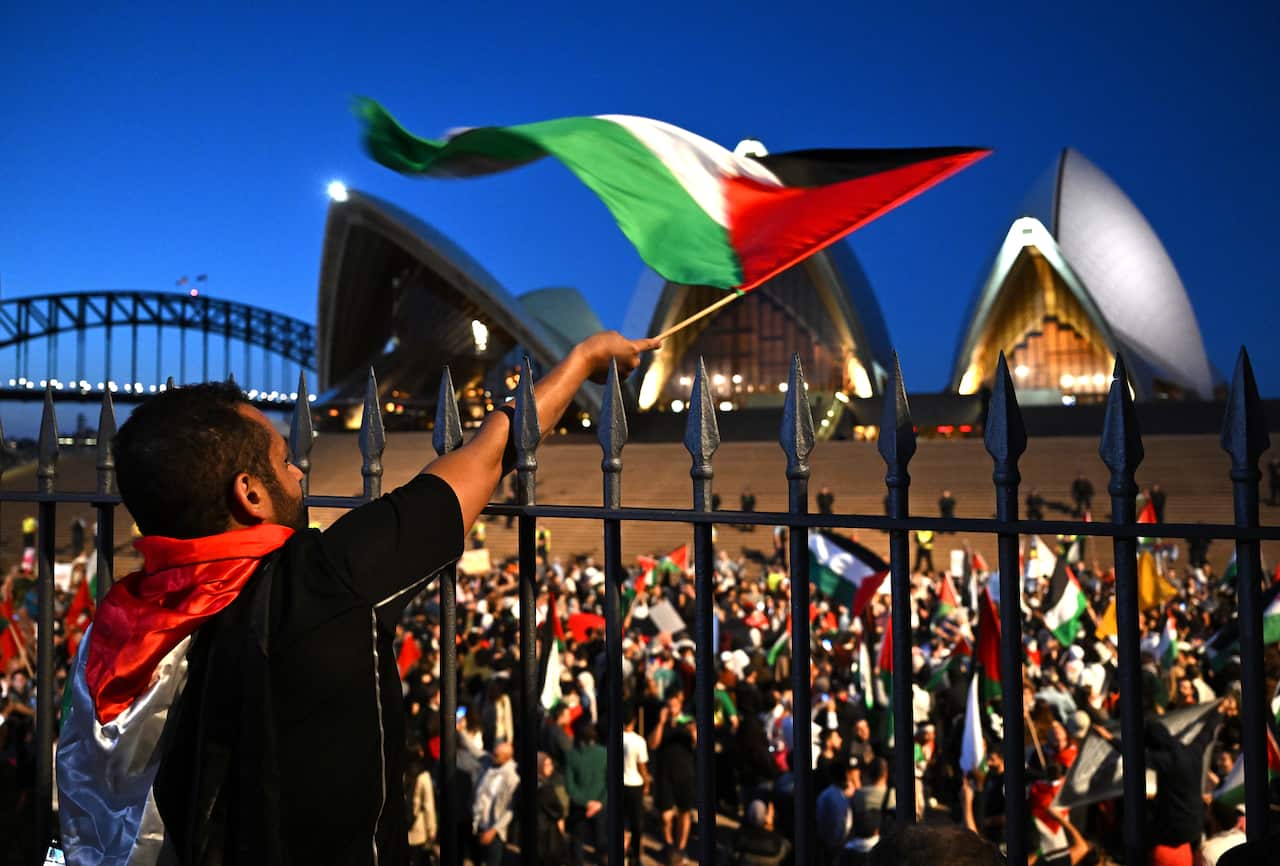 A large group of protesters on the Opera House forecourt, many waving Palestinian flags.