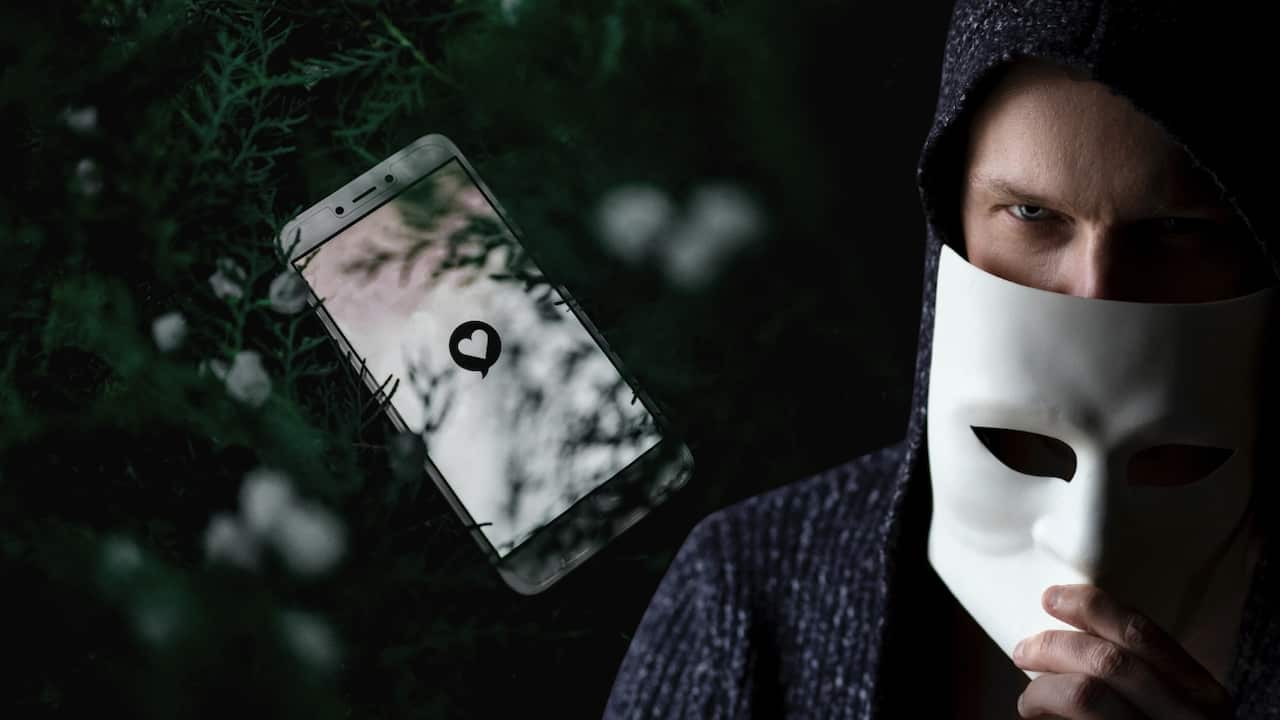 Criminal masking off with smartphone showing a dating app starting up in background