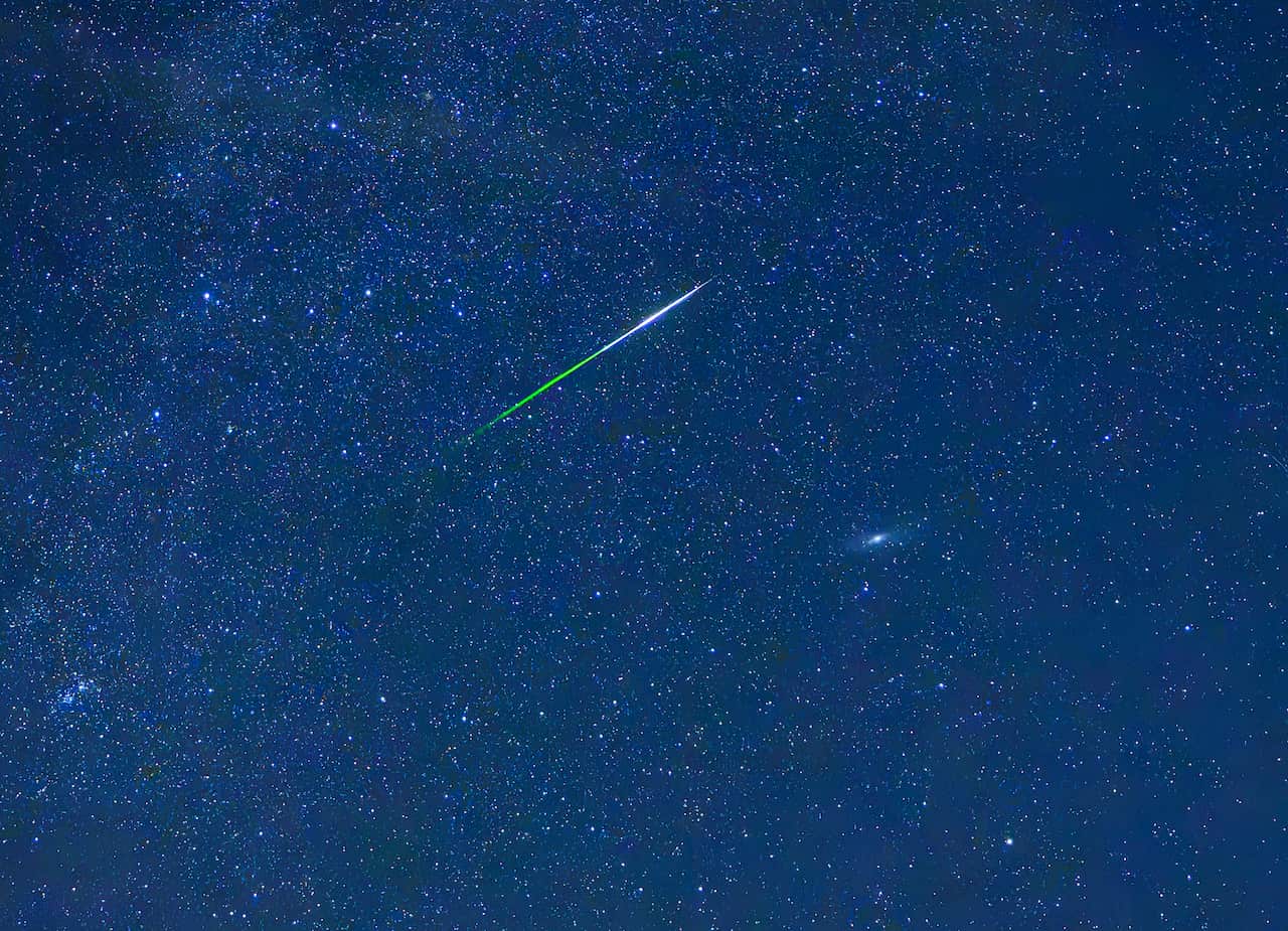 A meteor shower is visible in the blue skies.