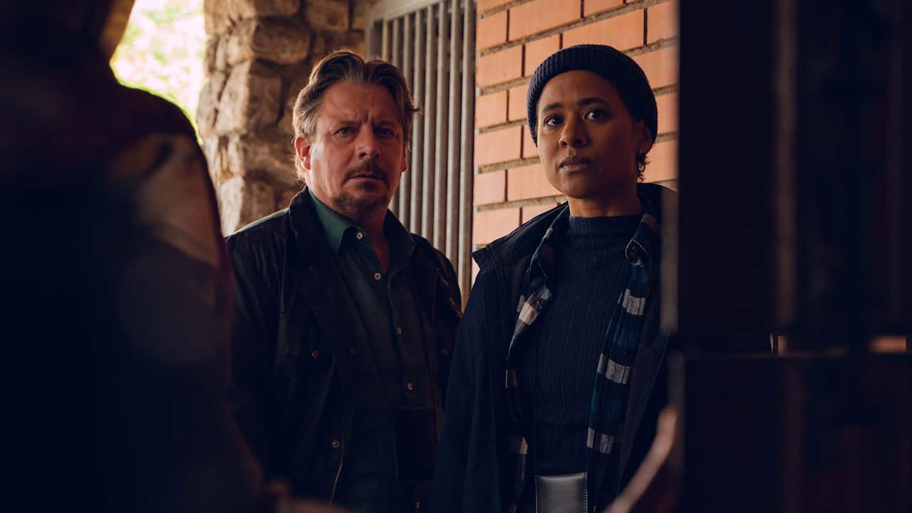 Danish actors Anders W. Berthelsen and Olivia Joof Lewerissa stand in a doorway as someone opens opens the front door to them in season 2 of DNA.jpg