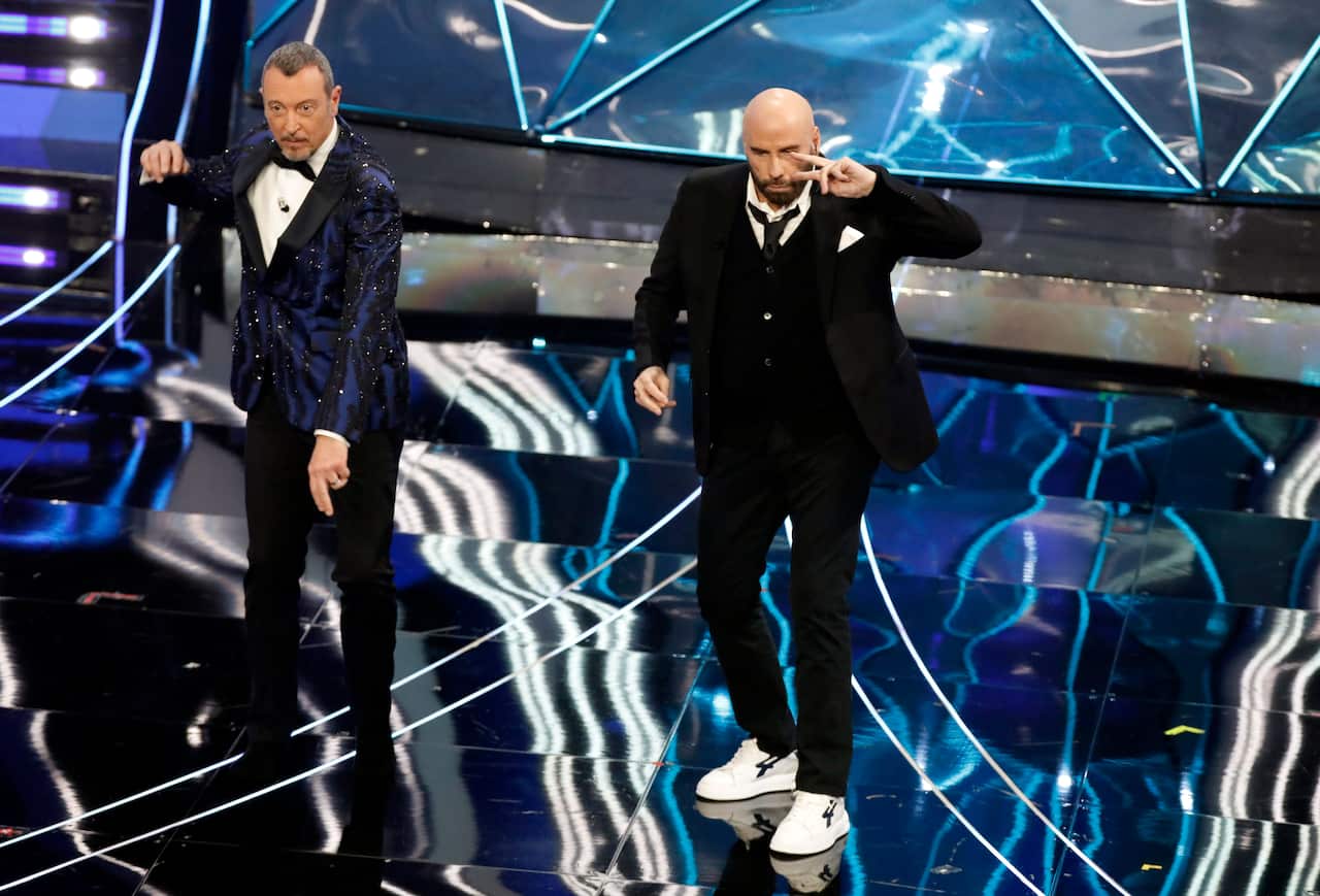Two men wearing formal attire dance on a stage.