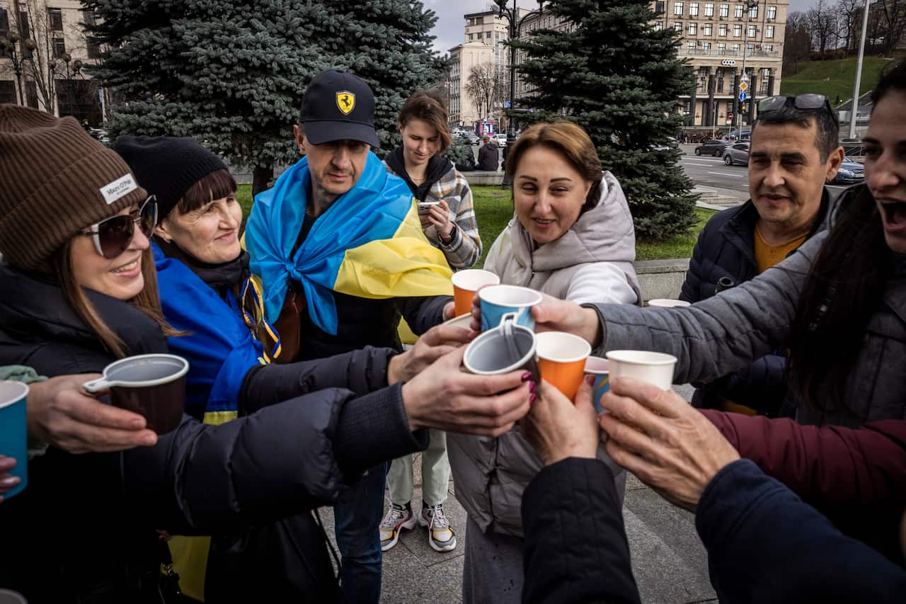 People drink sparkling wine, waves flags and sing songs as they celebrate the liberation of Kherson in Kyiv, Ukraine. 