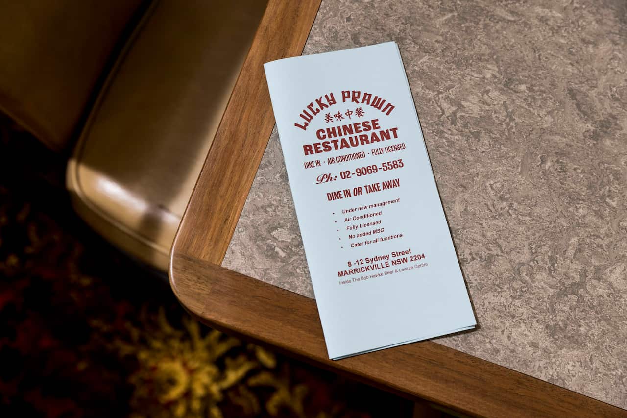 A paper menu for the Lucky Prawn sits on a table