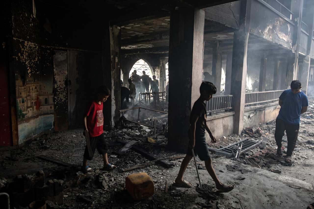 Children walking amongst rubble in a building that has been badly damaged.