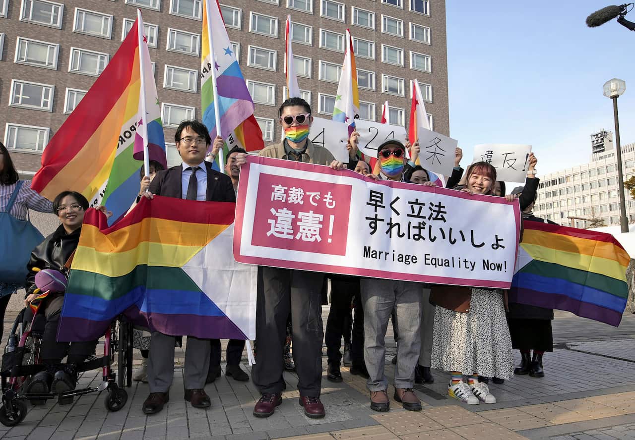 A group of people stand holding banners