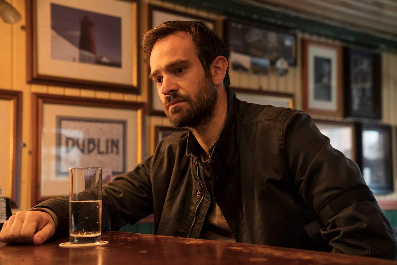 A man sits at a bar looking pensive with a glass of water in front of him.jpg