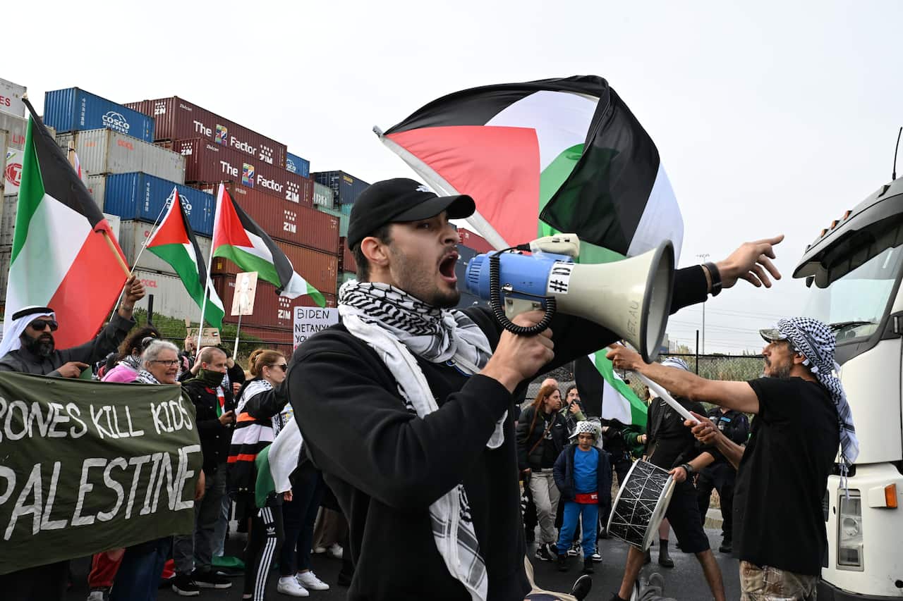 A man with a megaphone wearing a black and white scarf.