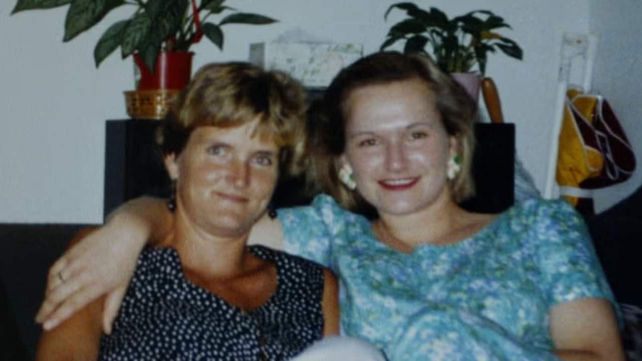 a vintage photo from the nineties of two young blonde women sitting together on a couch, the woman on the right has her arm around the other woman's shoulder