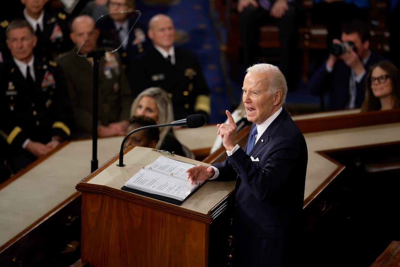 Joe Biden stands with his arm outstretched on the podium