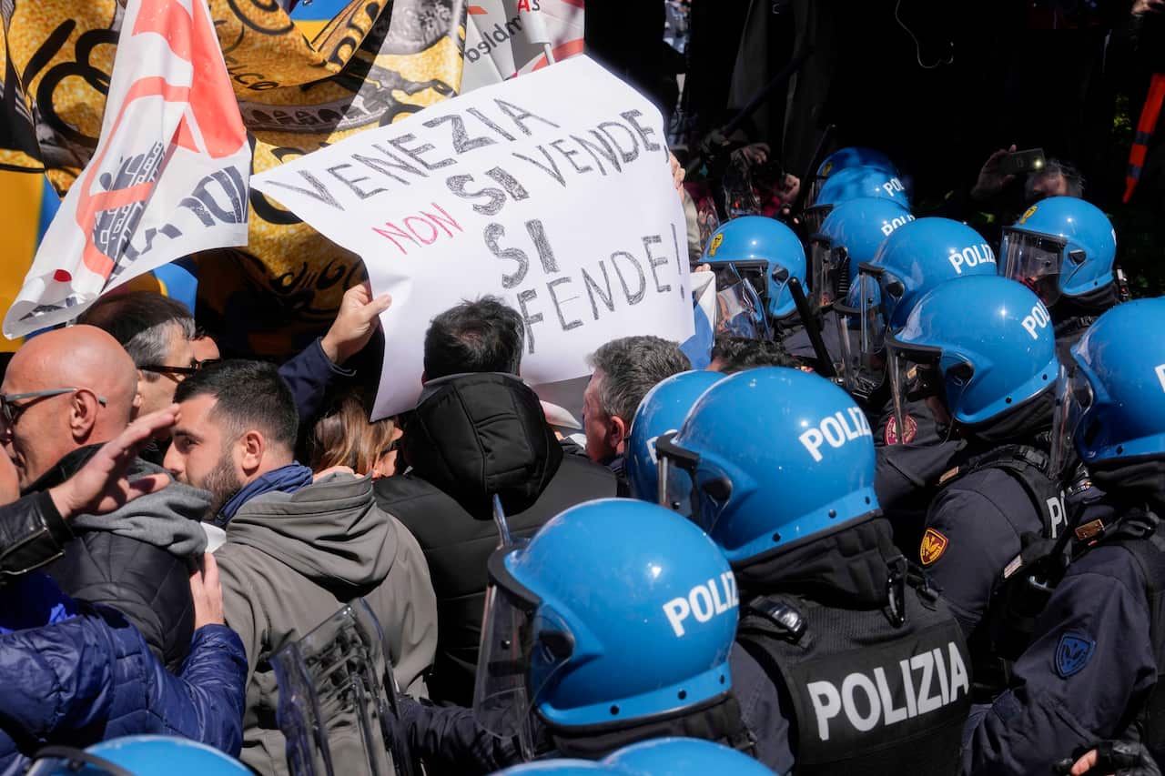 People carrying signs are crushed up against officers in riot gear