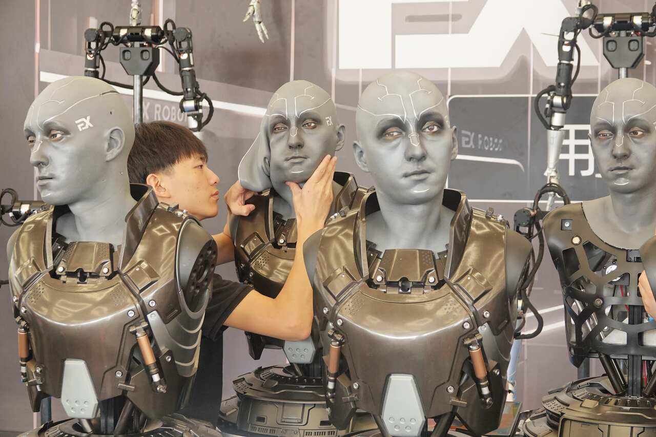 A man adjusts a robot's face.