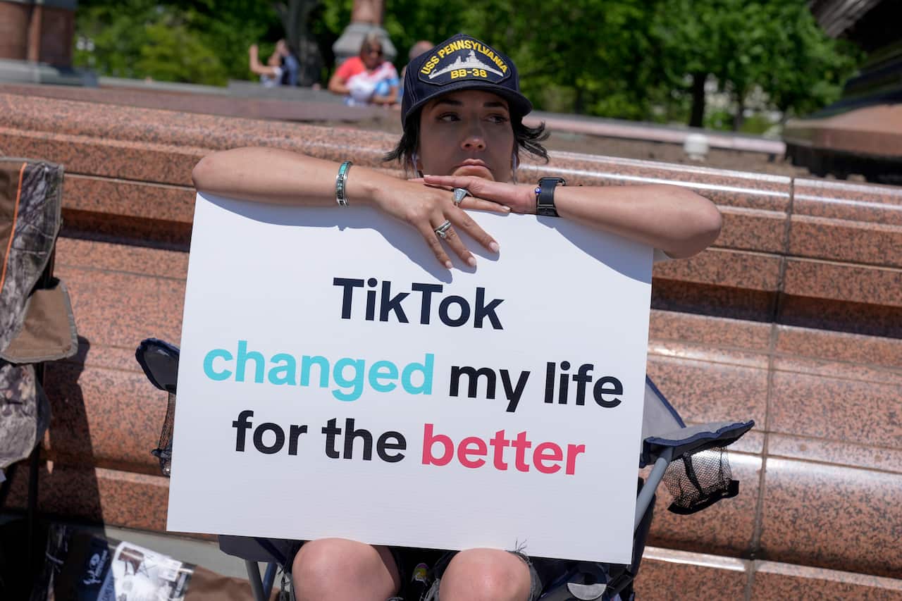 A person sits holding a sign