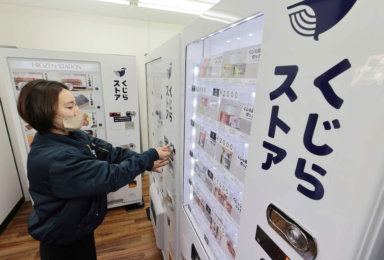 A woman checking a vending machine.
