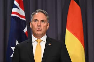 Richard Marles, standing in front of Australian and Aboriginal flags.