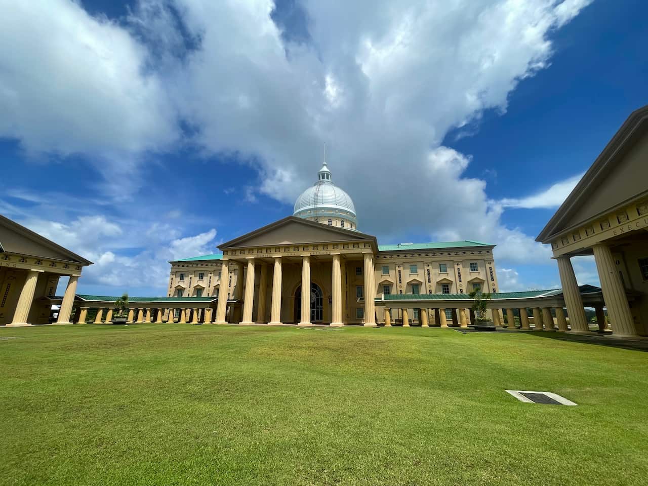 A low shot of a a building with a white dome and columned facade overlooking the surrounding landscape.
