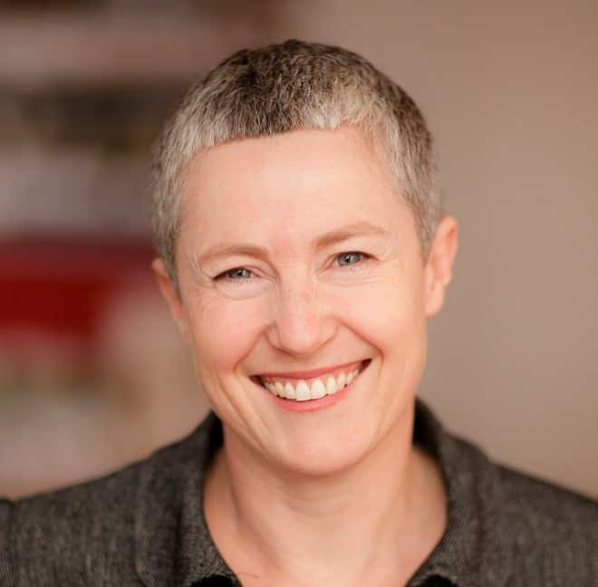 A woman with light-coloured short cropped hair smiling for the camera 