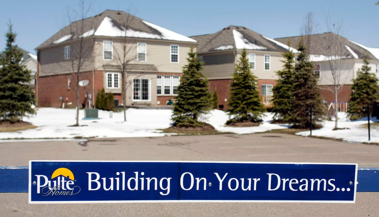 Newly built houses stand infront of a PulteHomes sign that says "building your dreams."