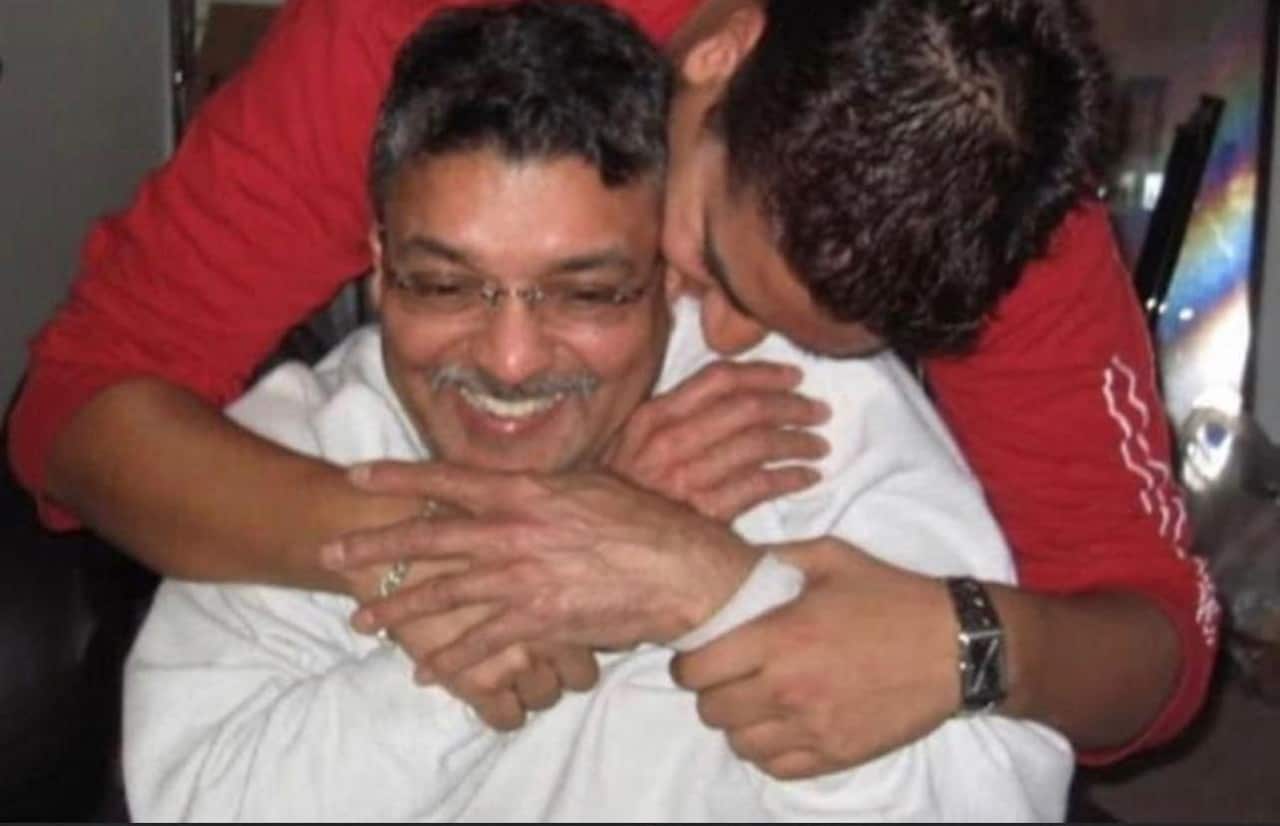 A man hugs his father, with both of them smiling.