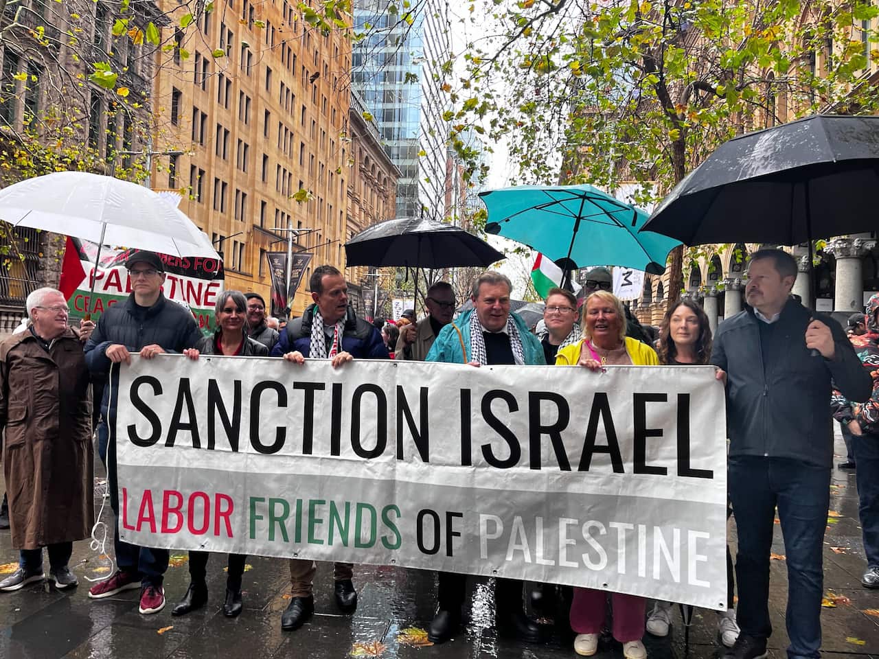 Several people hold up a white banner reading "SANCTION ISRAEL. LABOR FRIENDS OF PALESTINE"
