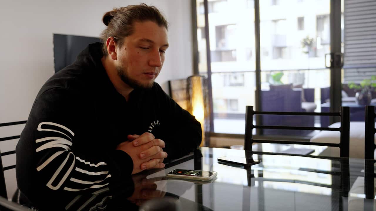 A man sits at a table with his mobile phone.
