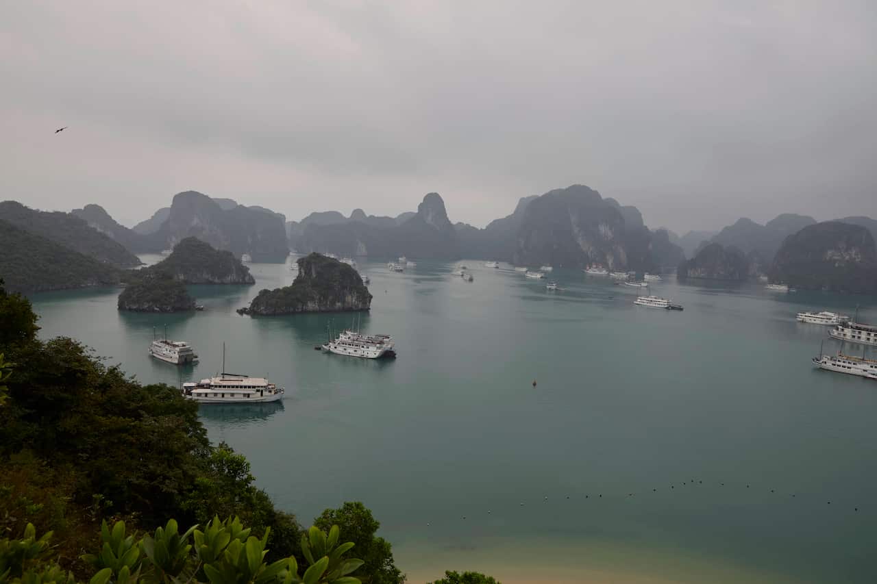 Vessels sail through a calm bay surrounded by limestone formations.