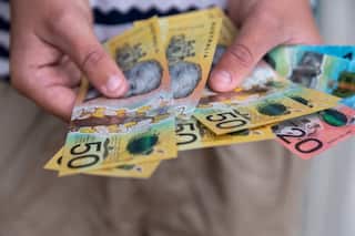 A pair of hands holding an assortment of Australian cash
