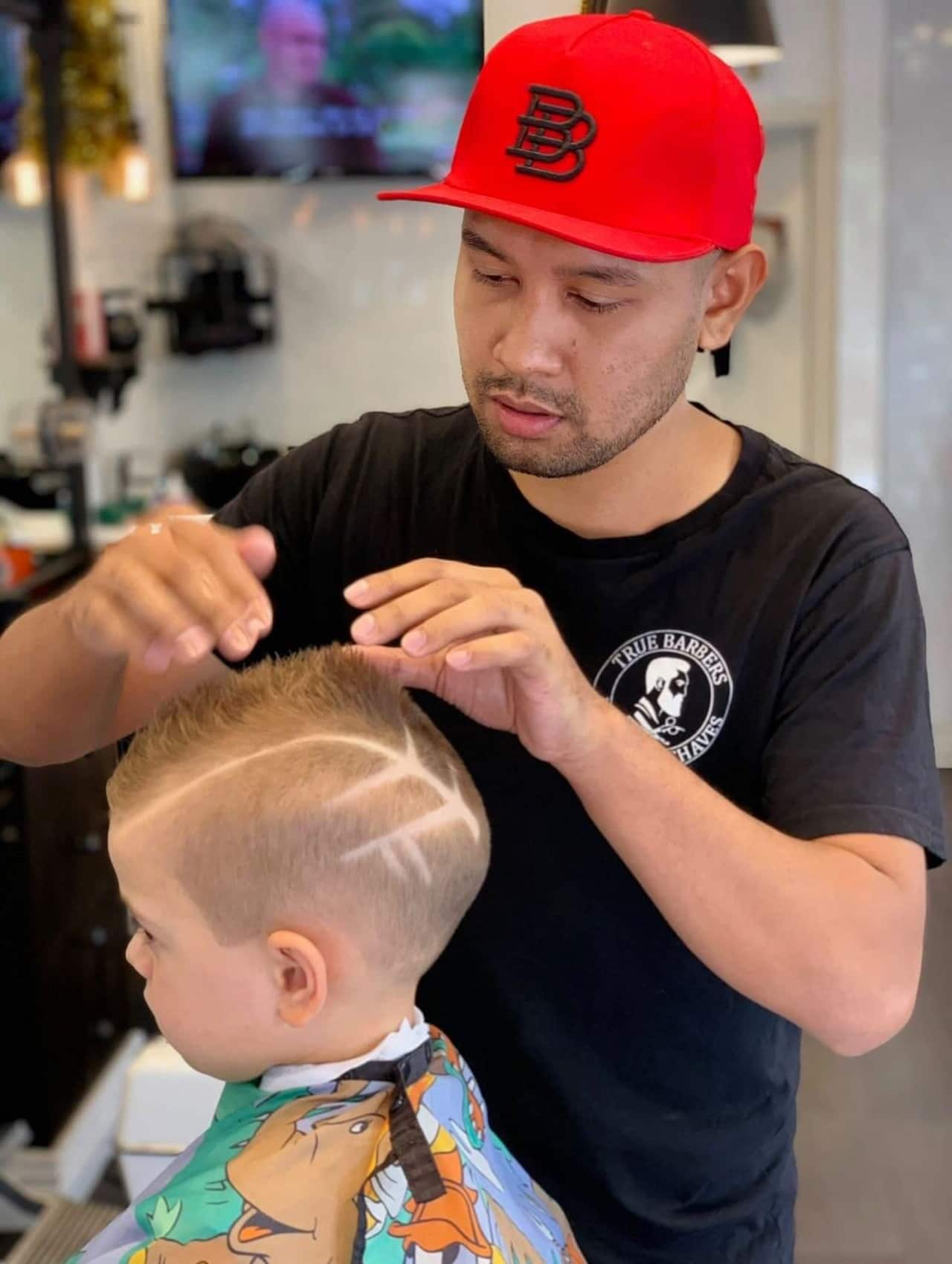 คุณศักรินทร์ขณะตัดผมเด็กผู้ชาย