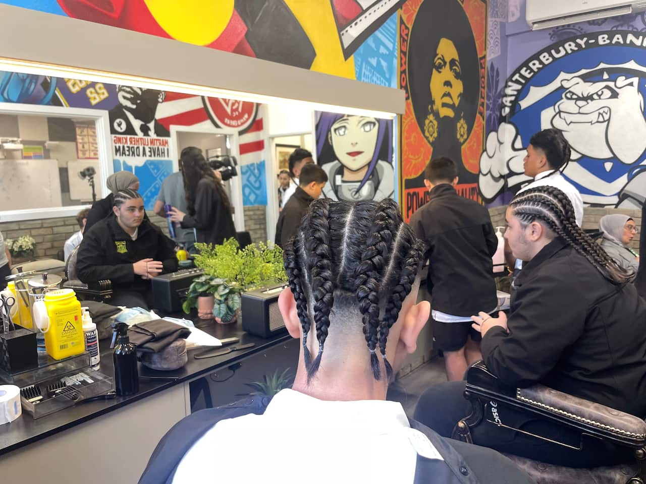 Boys have their hair braided in a salon. 
