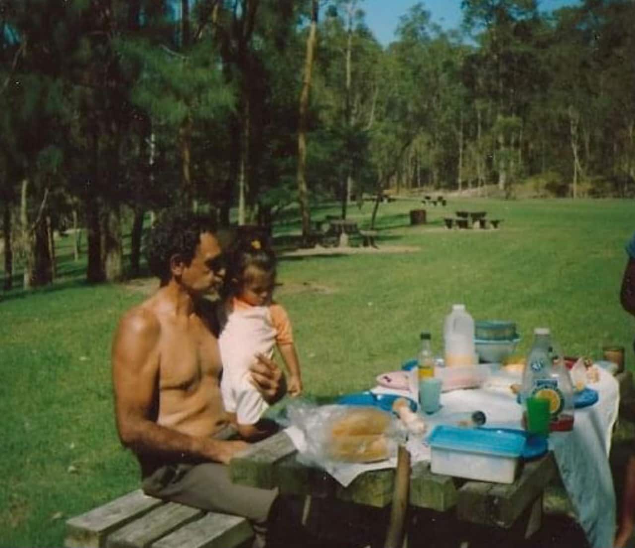 Kumarah as a child, sitting on her grandfather, Ray Kelly Senior's lap. Ray Kelly Senior is known for his work identifying sacred sites in New South Wales.