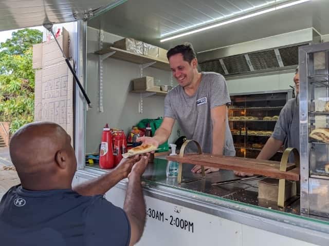 Lachlan McDaniel serves sausage rolls and coffee to locals in Lismore on Saturday. 