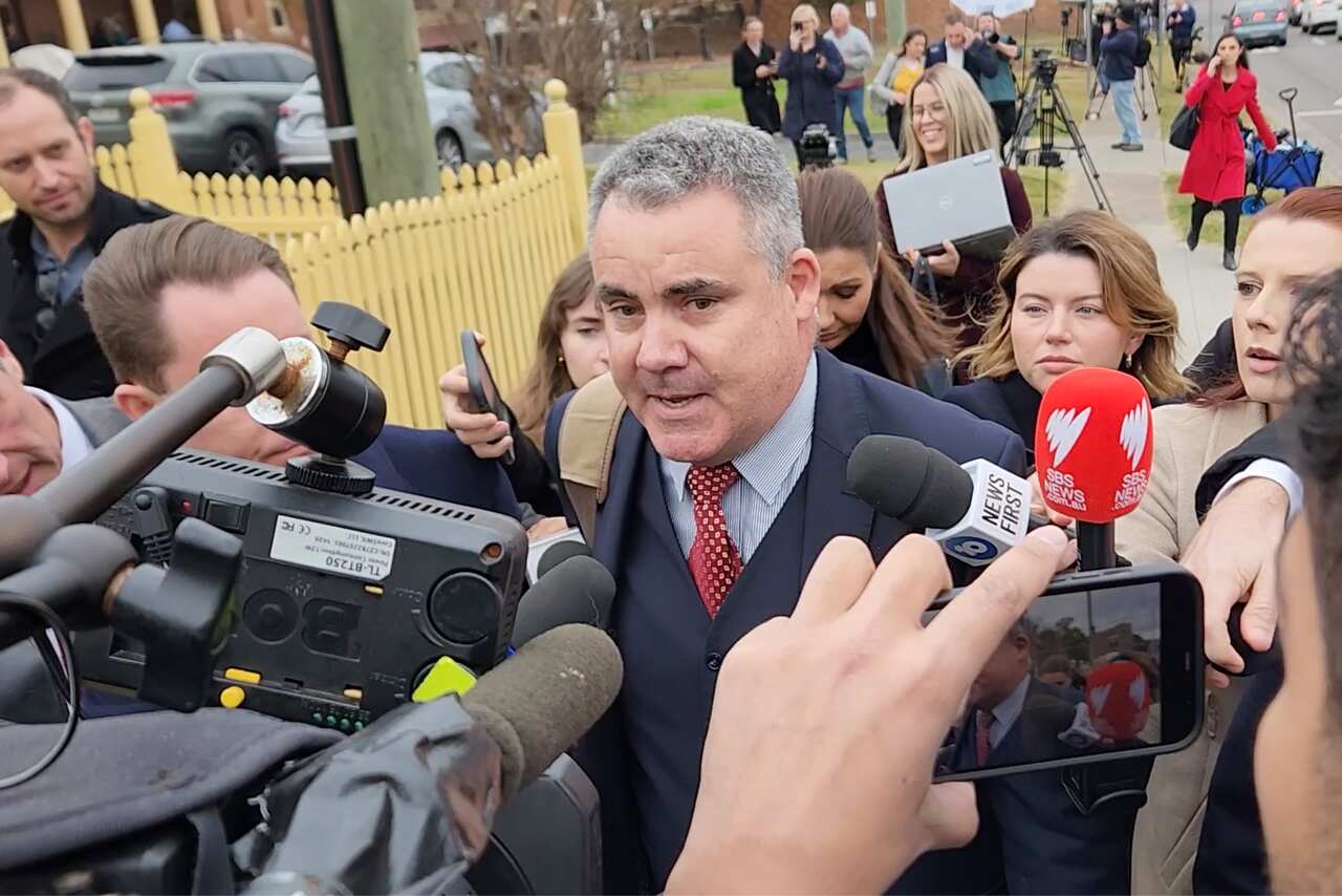 A man in a suit speaking to news reporters outside a court.