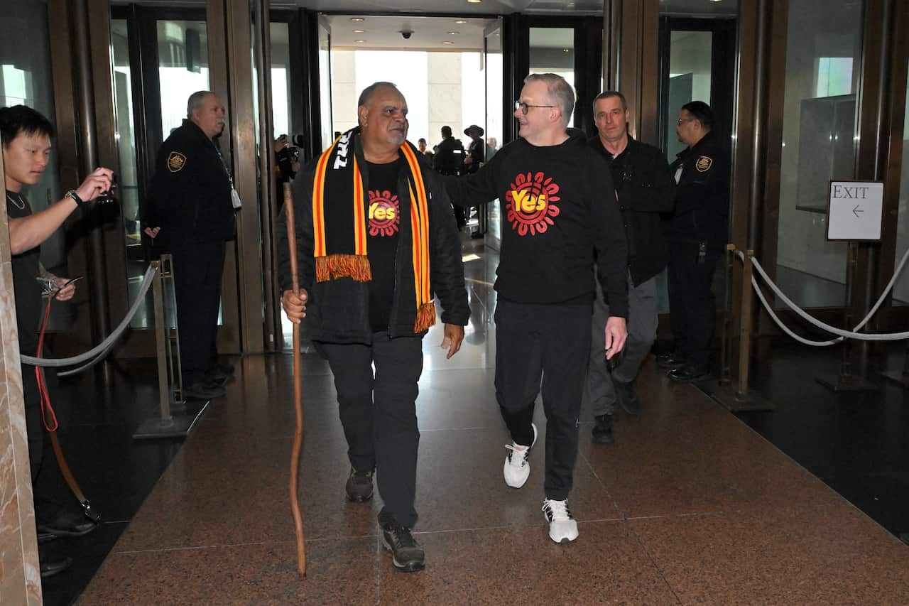 Anthony Albanese touches Michael Long's back. They are both wearing Yes campaign T-shirts.