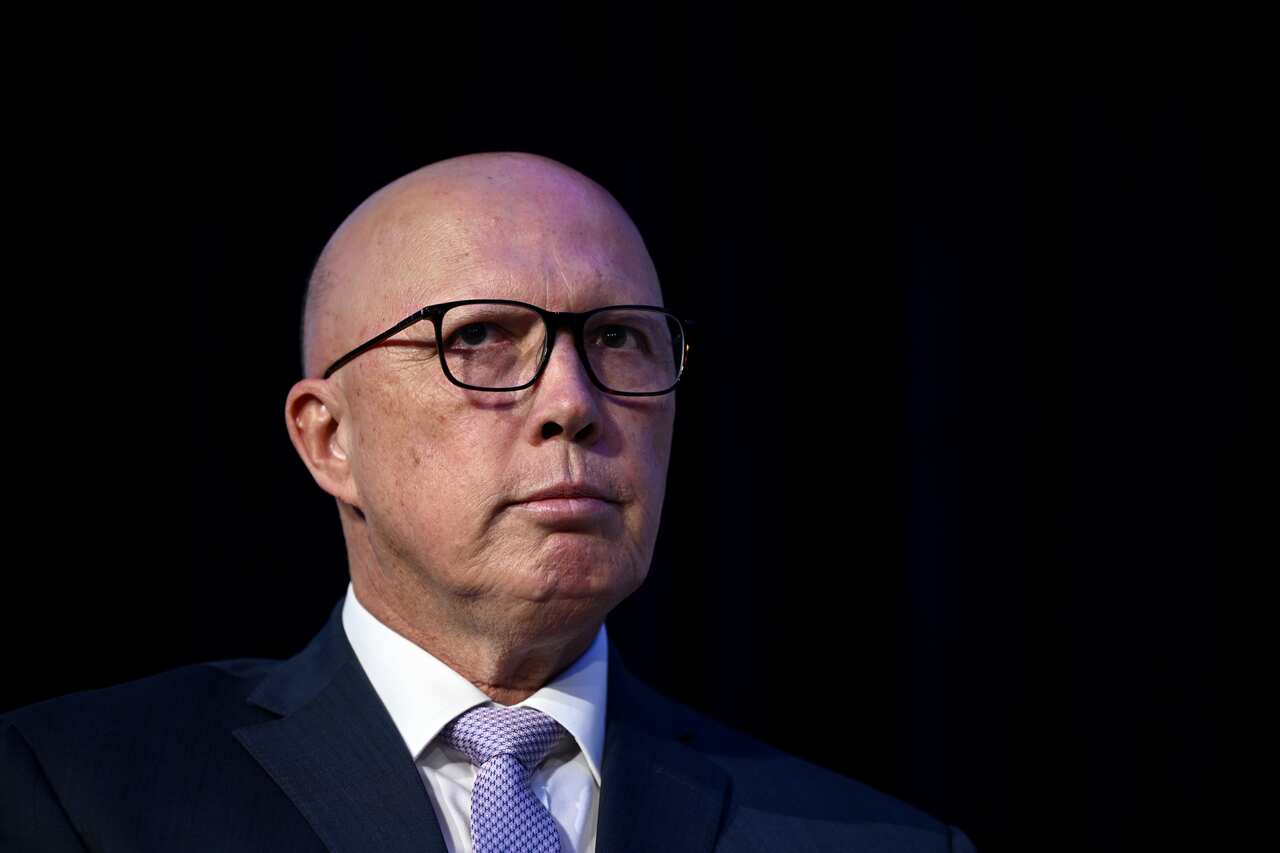 A man wearing a suit and glasses against a black background
