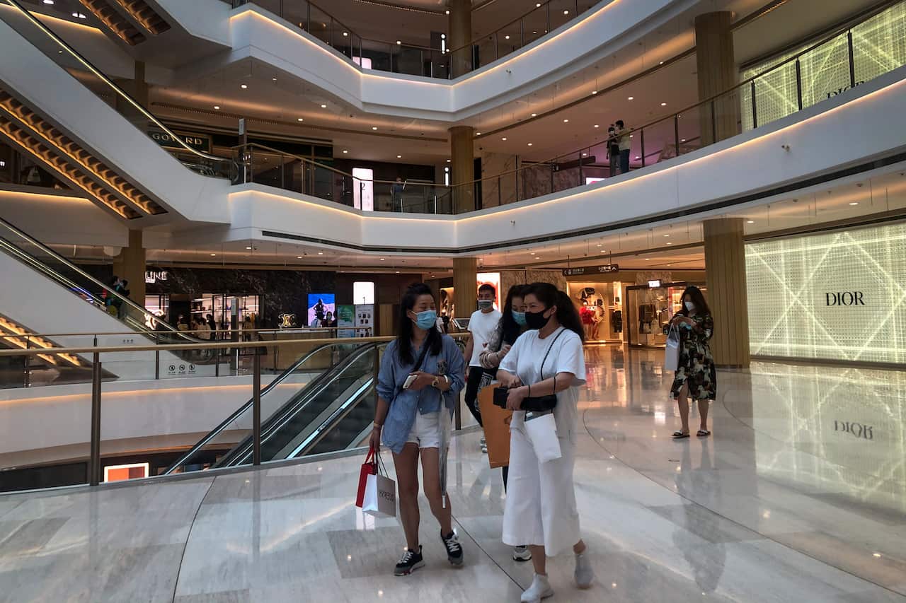 Shoppers wearing face masks walk through a reopened shopping mall in Shanghai