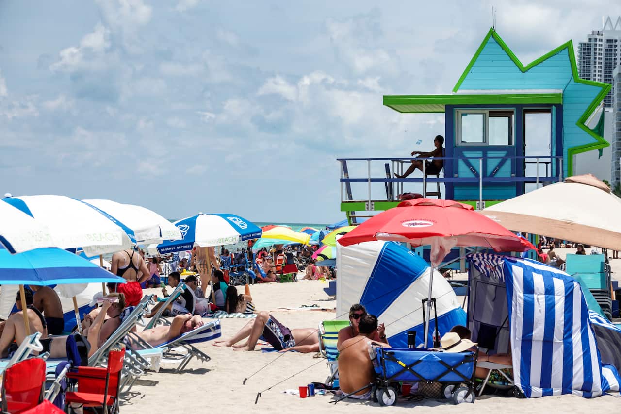 A crowded beach with many large umbrellas set up.
