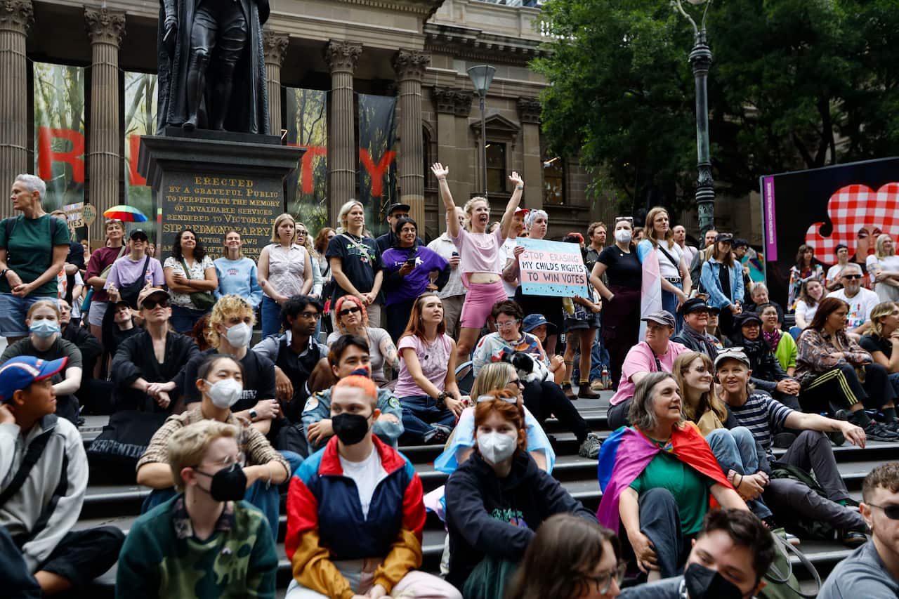 Protesters are sitting on the steps outside a library building.
