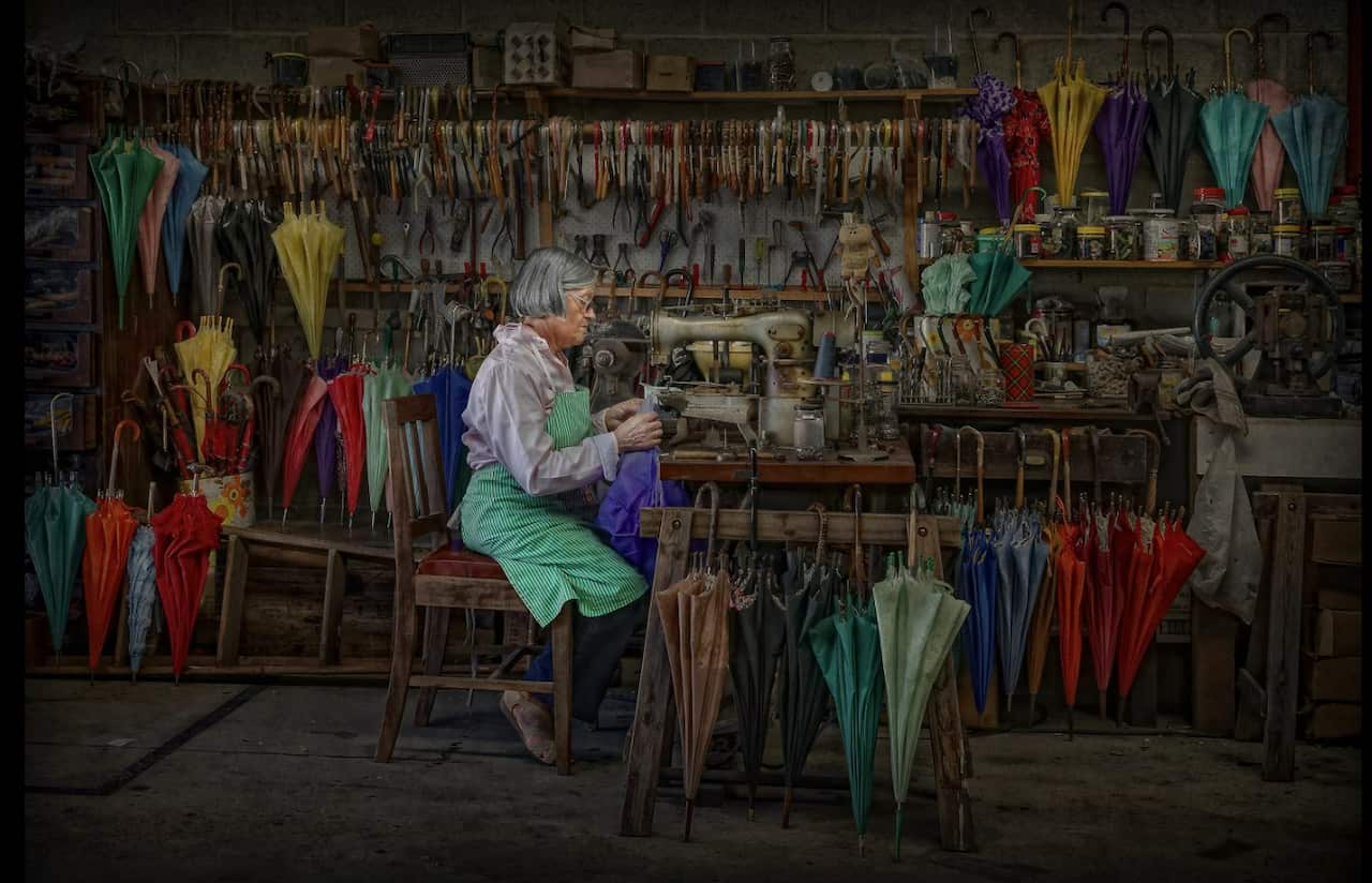 Painting of a women making handmade umbrellas in a workshop.