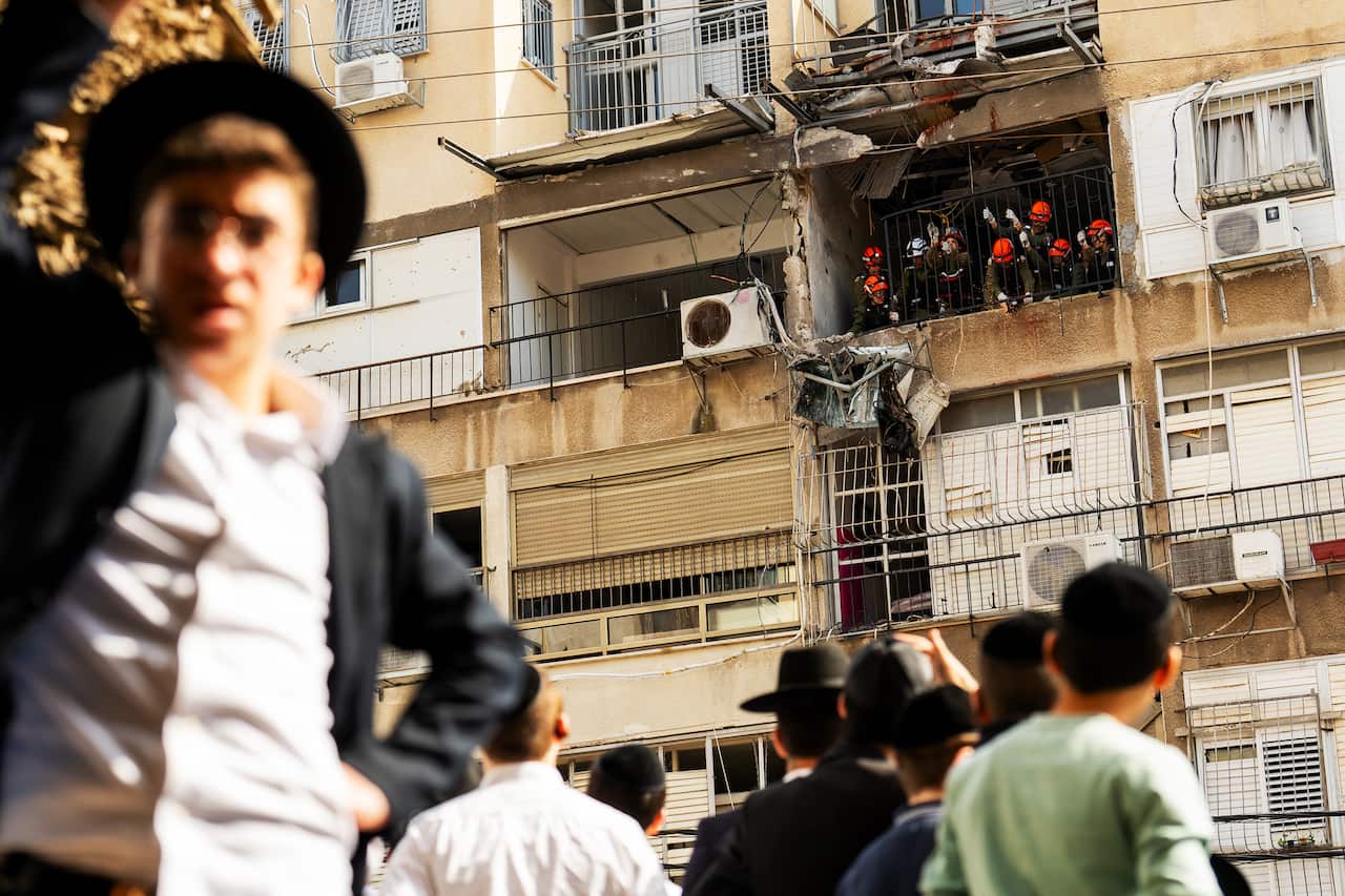 Israeli nationals gather at site of an Iranian missile strike in Bnei Brak on 15 March 2026