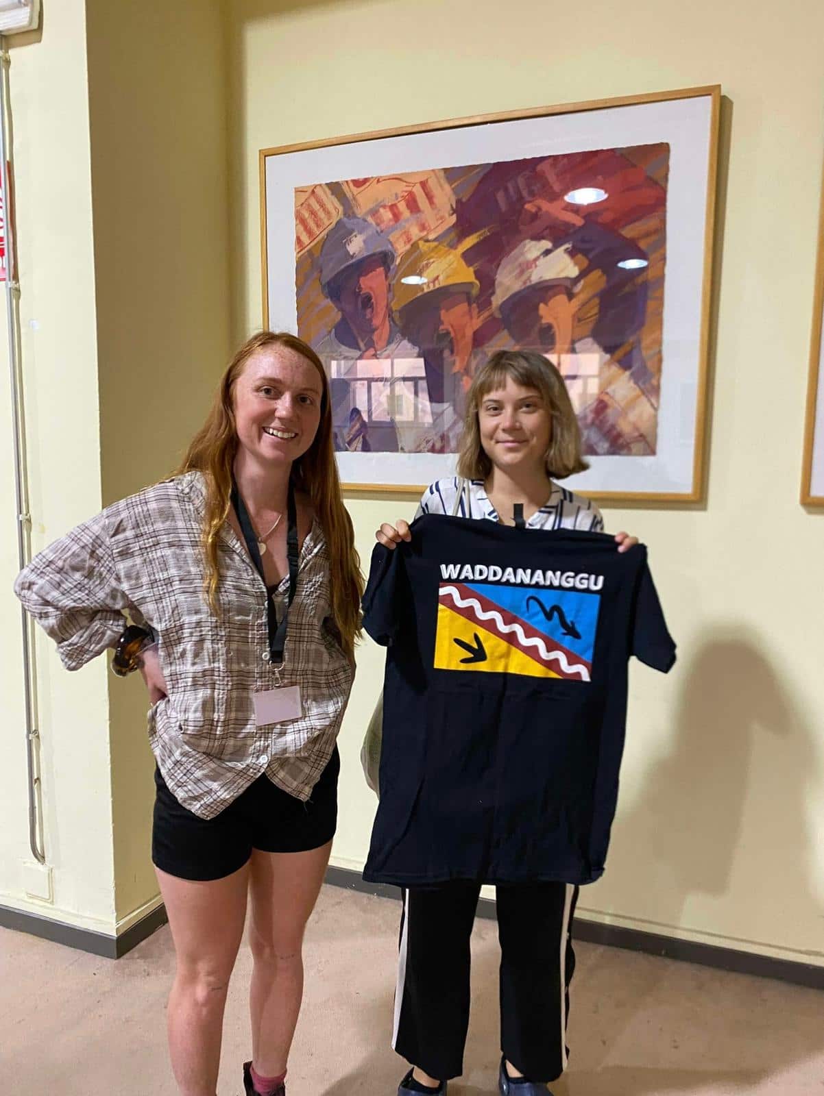 A young woman stands next to a woman holding a black T-shirt.