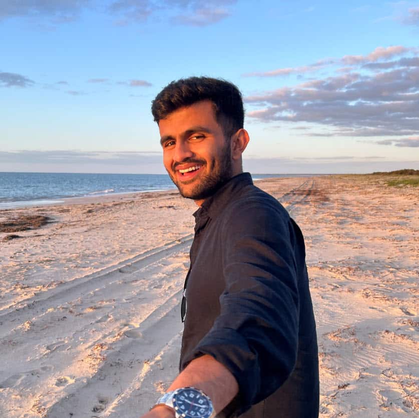 A young man looks at the camera he is holding with a selfie stick.