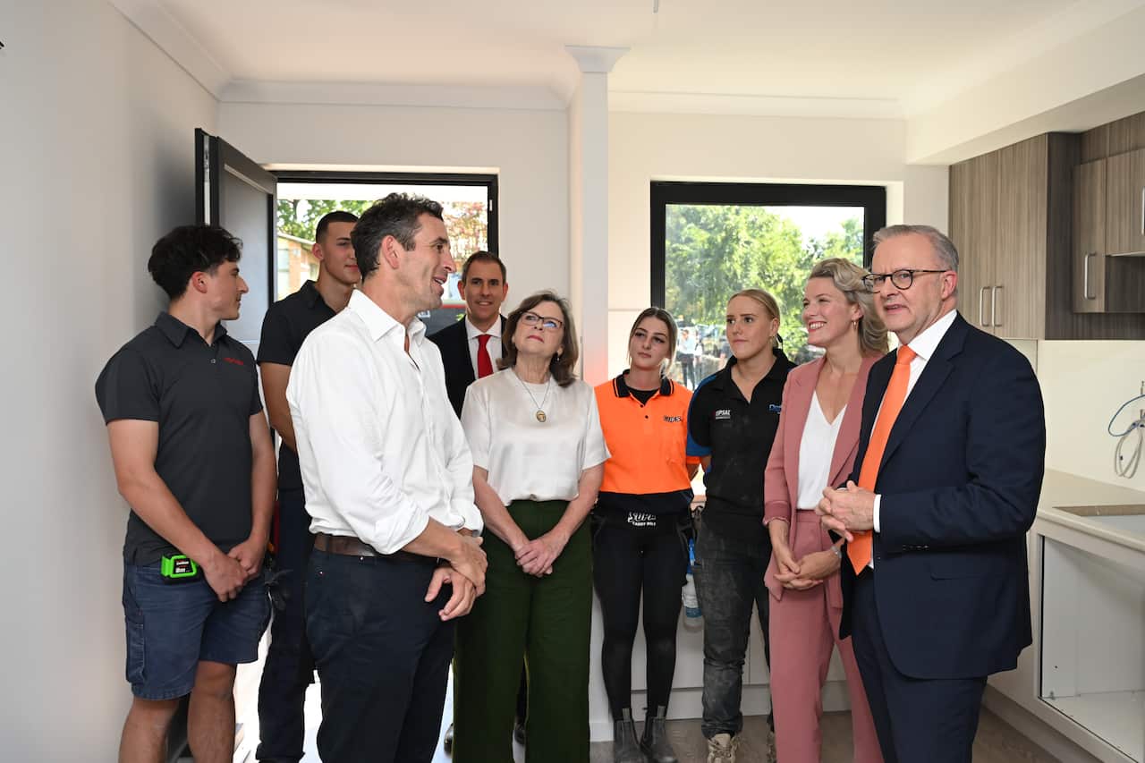 Anthony Albanese stands inside a house flanked by members of his team. 