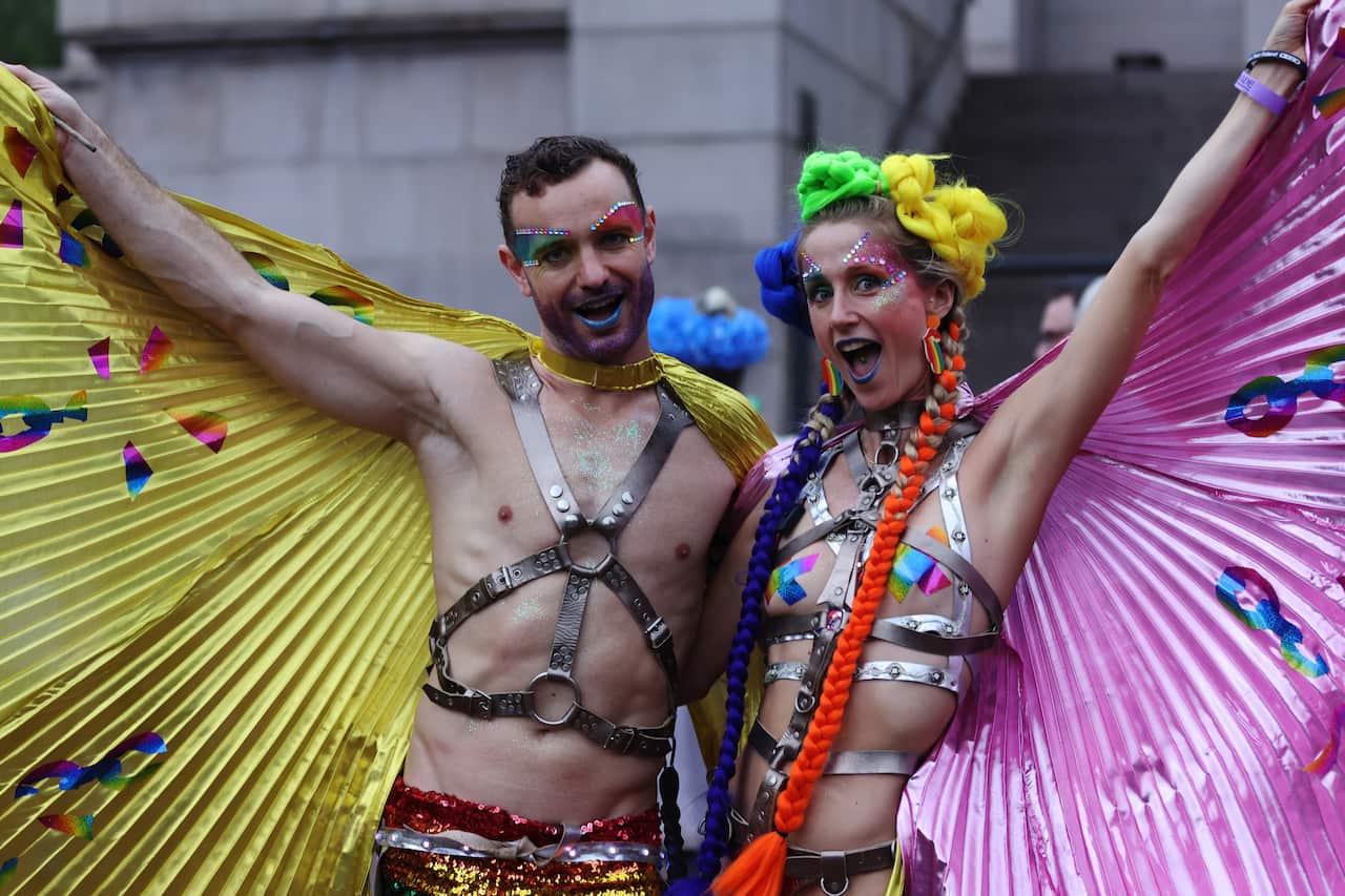 Two people with colourful capes and makeup dressed up for Mardi Gras
