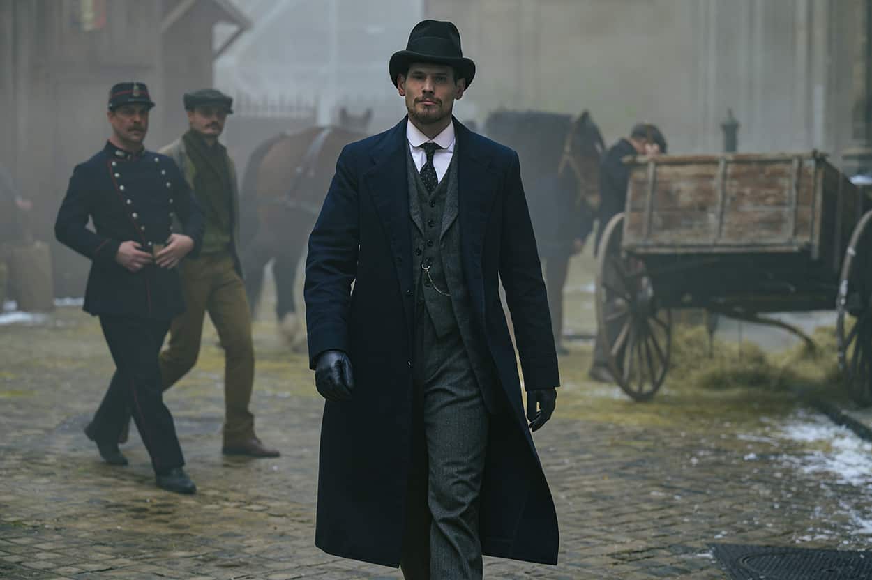 Historical setting: Man in long coat and hat strides through a foggy street